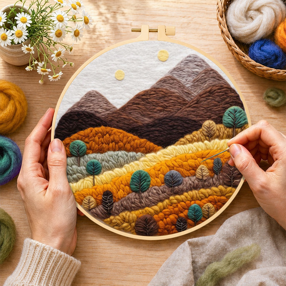 Creating the earthy brown and burnt orange mountains with trees wool painting by hand with a felting needle
