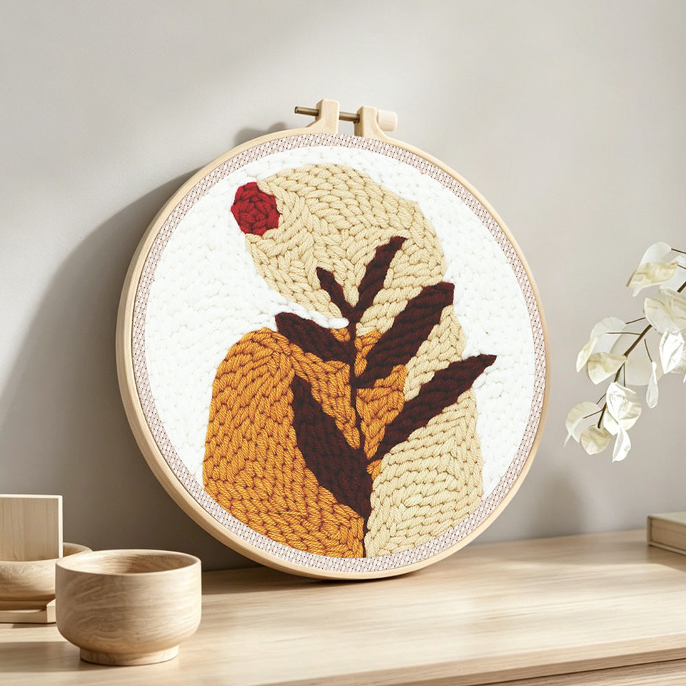 Earthy tones botanical leaf punch needle artwork displayed on a table