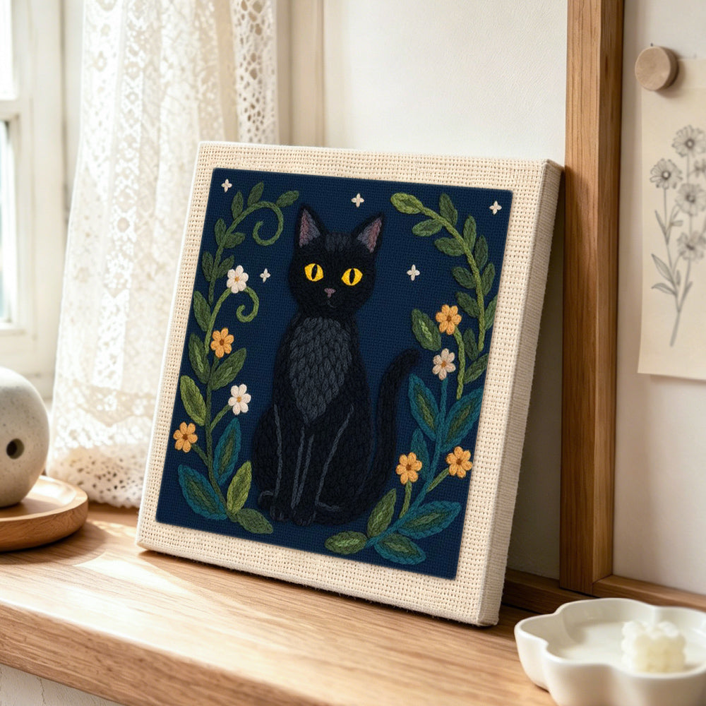 Elegant black cat and botanical punch needle artwork displayed on a table