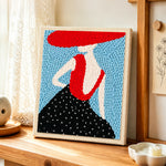 Elegant woman in red hat punch needle artwork displayed on a table