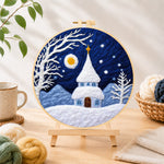 Finished fairy tale snowy spire cottage needle felting displayed on a wooden easel