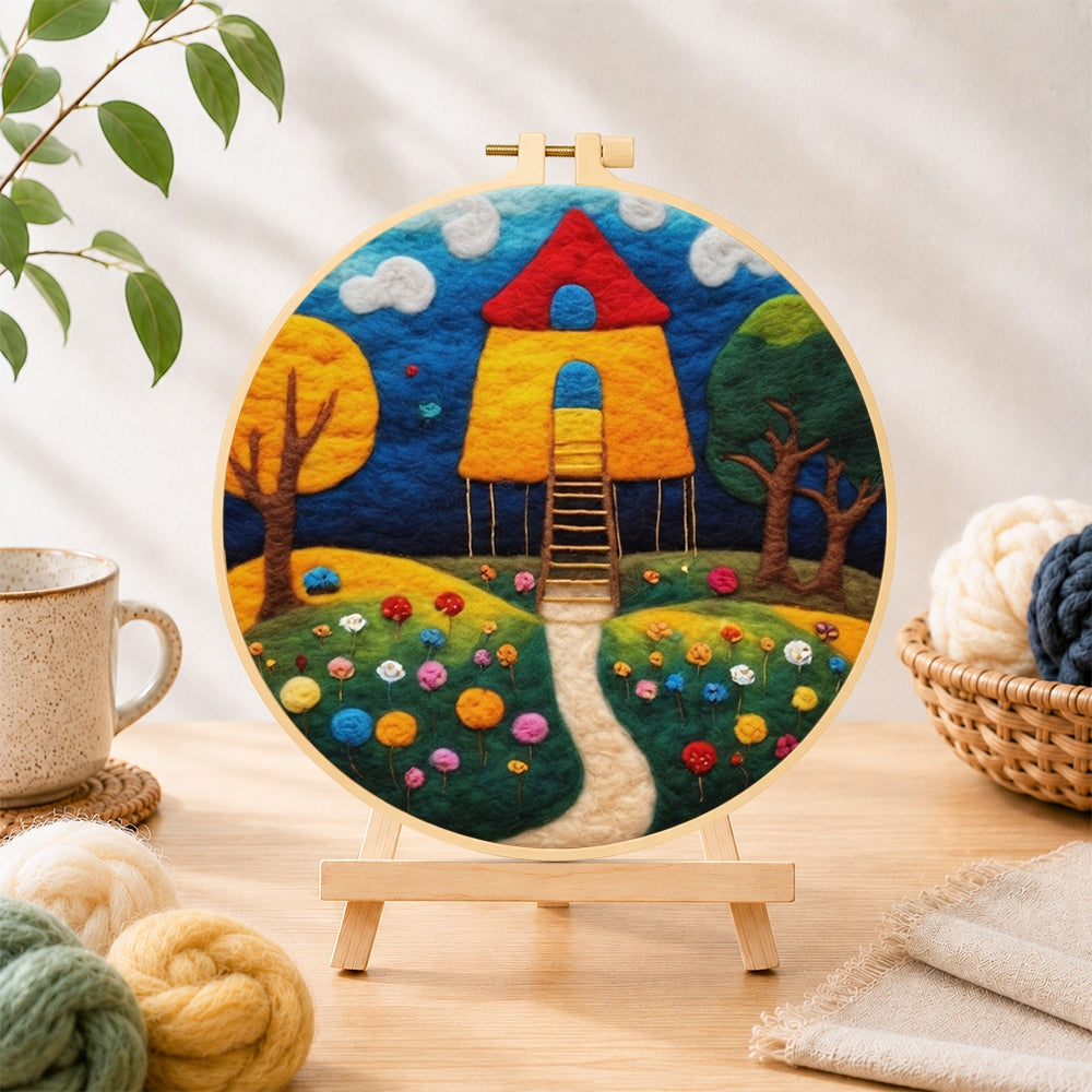 Finished fairy tale tall red roof cottage needle felting displayed on a wooden easel