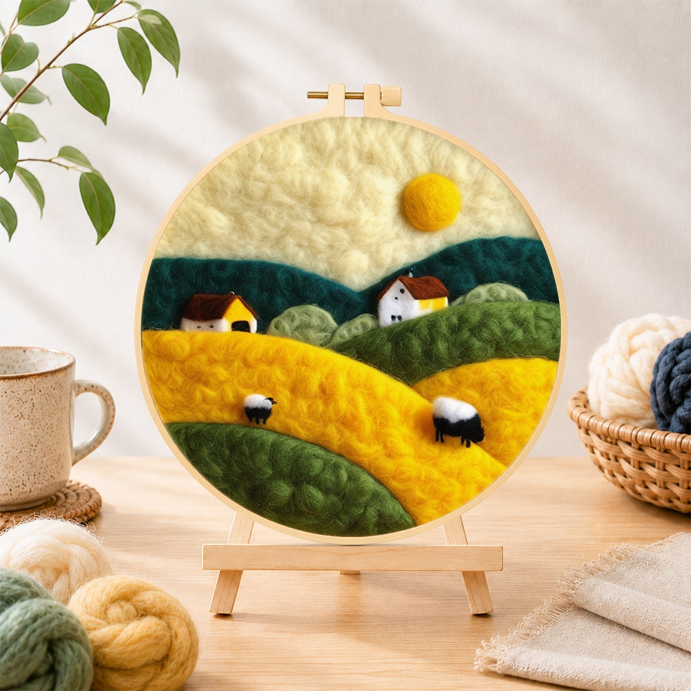 Finished farmhouses and rolling hills needle felting displayed on a wooden easel