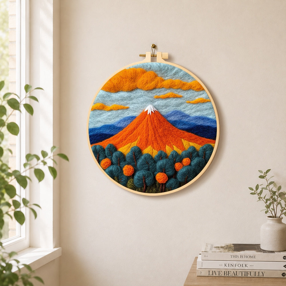 Fiery red volcano and deep blue trees needle felt wall art displayed in a bright home interior