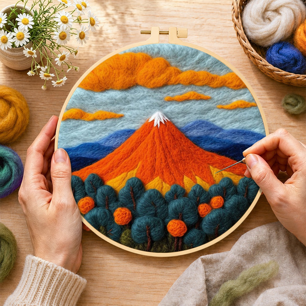 Creating the fiery red volcano and deep blue trees wool painting by hand with a felting needle
