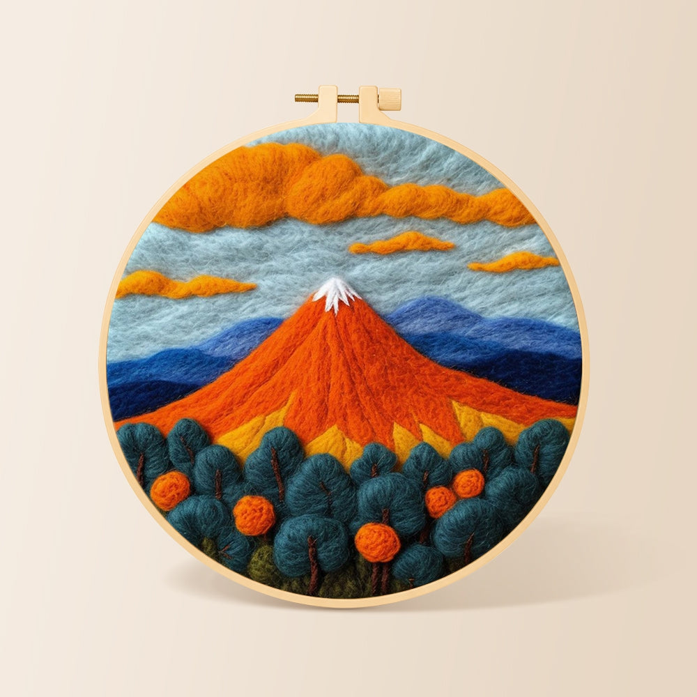 Fiery red volcano and deep blue trees needle felting kit for beginners with a round wooden frame