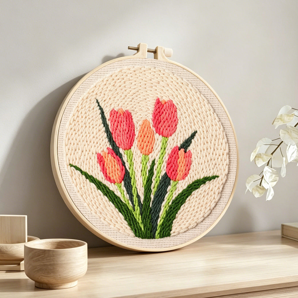 Five coral tulips in bloom punch needle artwork displayed on a table