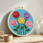 Five vibrant roses punch needle artwork displayed on a table