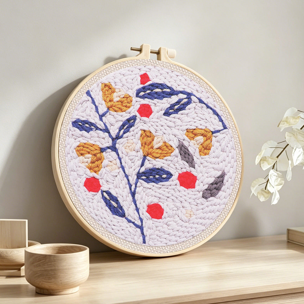 Floral branch with red berries punch needle artwork displayed on a table