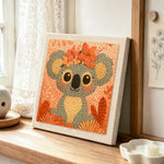 Floral crown koala punch needle artwork displayed on a table