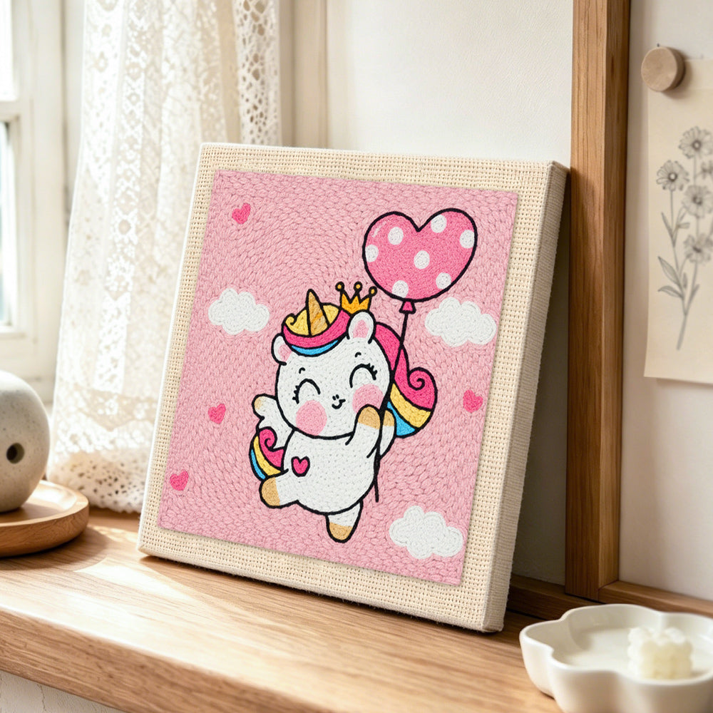 Flying unicorn with heart balloon punch needle artwork displayed on a table