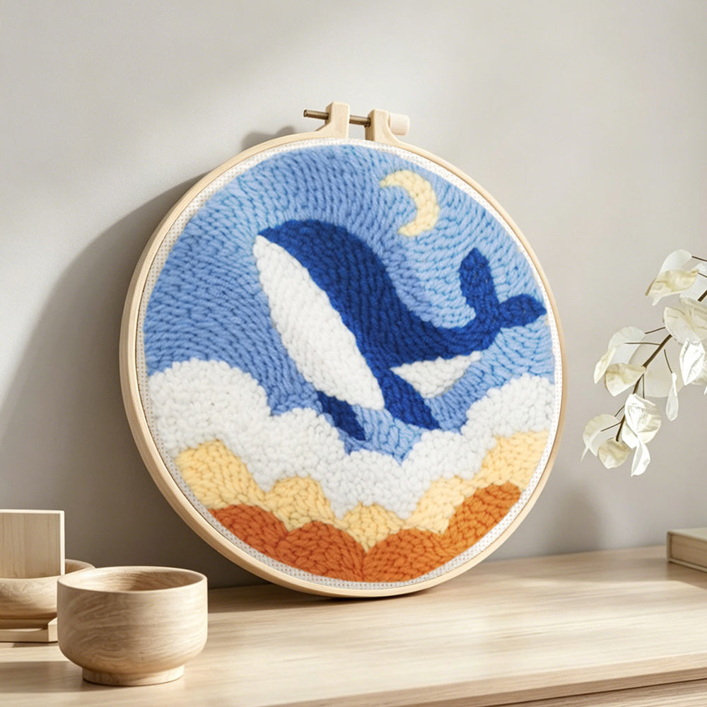 Flying whale in the sky with clouds punch needle artwork displayed on a table