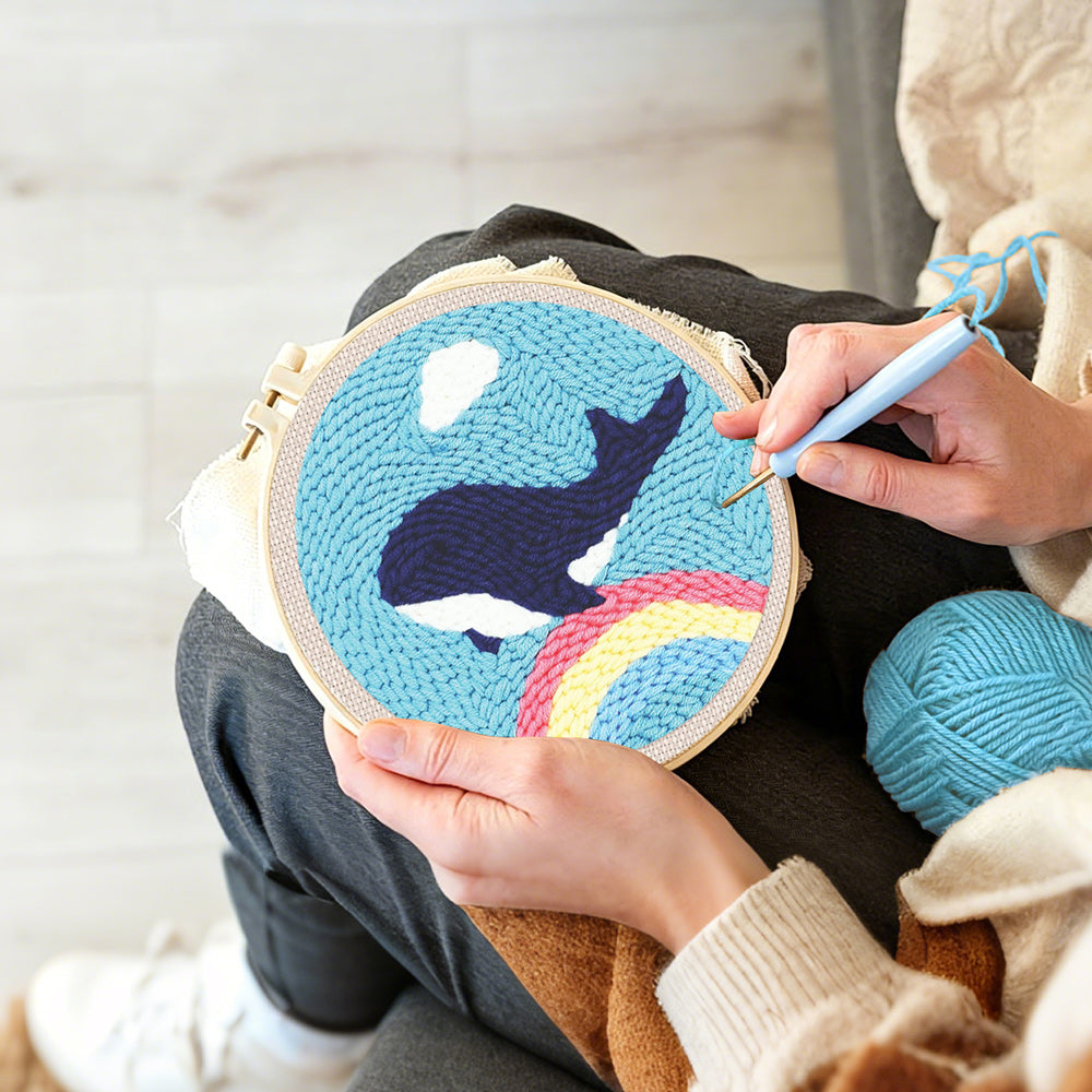 Creating handmade flying whale over rainbow in blue sky punch needle artwork