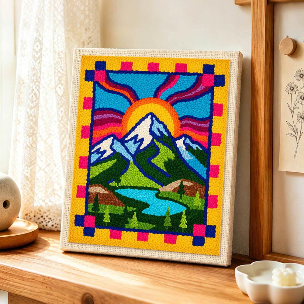 Folk art style mountains and sun rays punch needle artwork displayed on a table