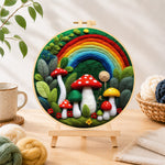 Finished forest rainbow and red mushrooms needle felting displayed on a wooden easel