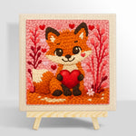 Fox holding a red heart punch needle kit for beginners