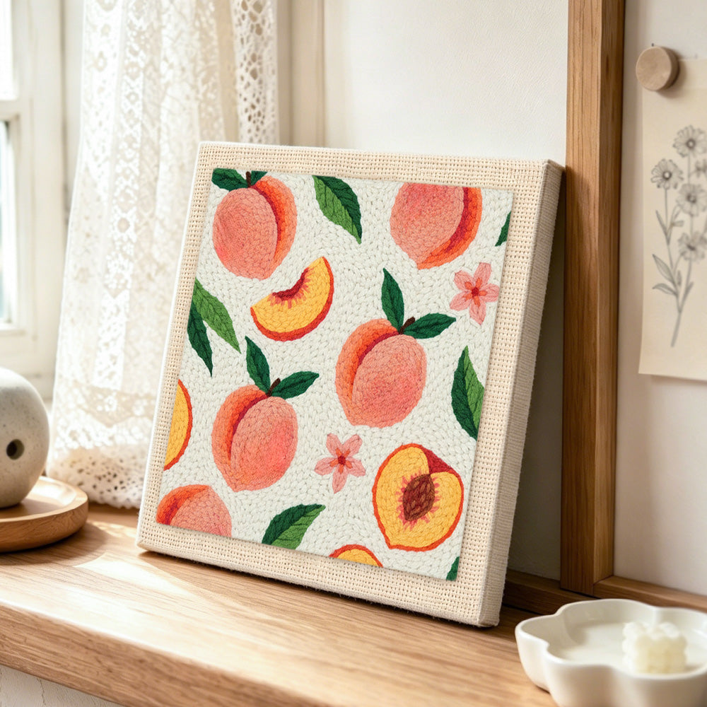 Fresh peaches with leaves punch needle artwork displayed on a table