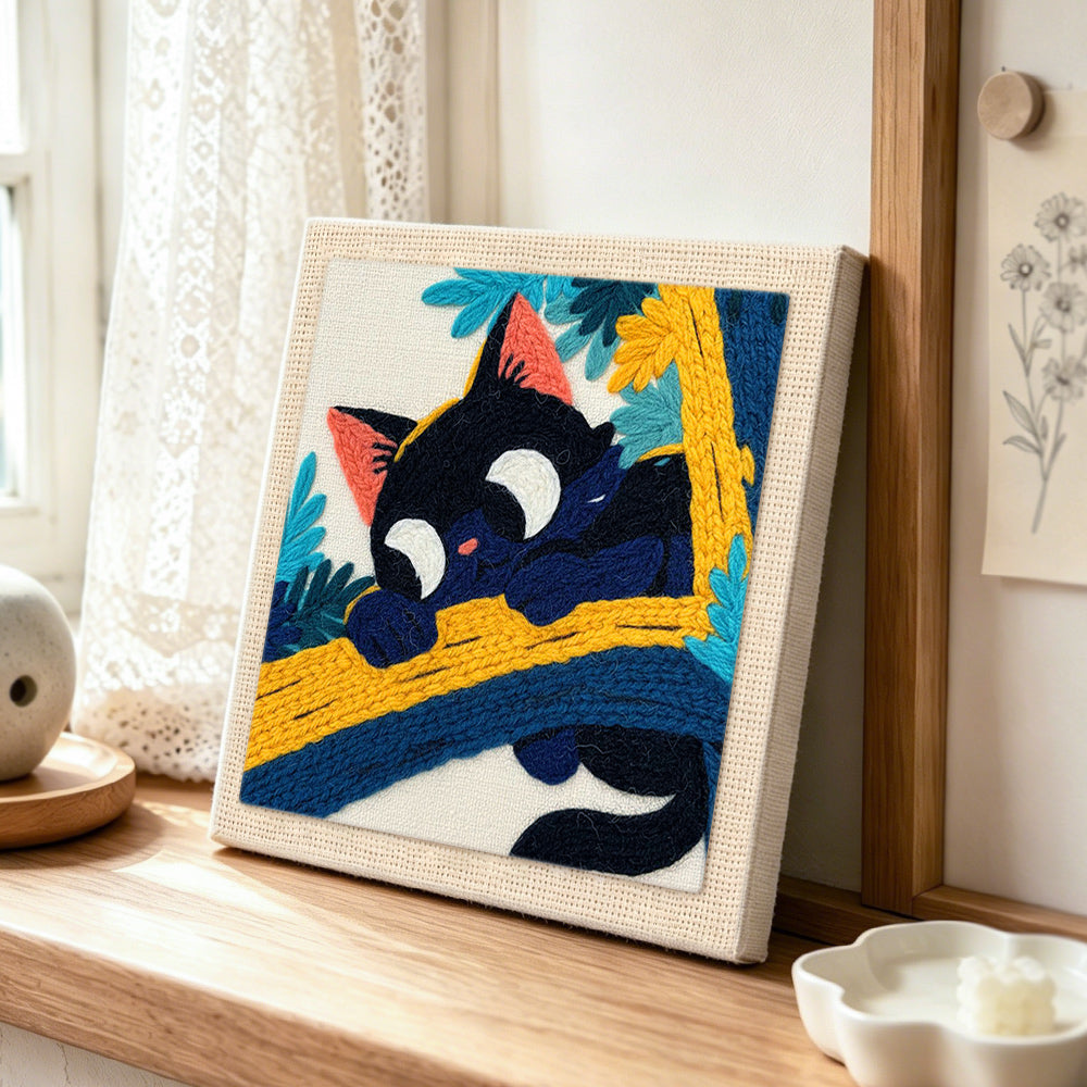 Funny black cat on a branch punch needle artwork displayed on a table