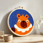 Funny orange squirrel punch needle artwork displayed on a table