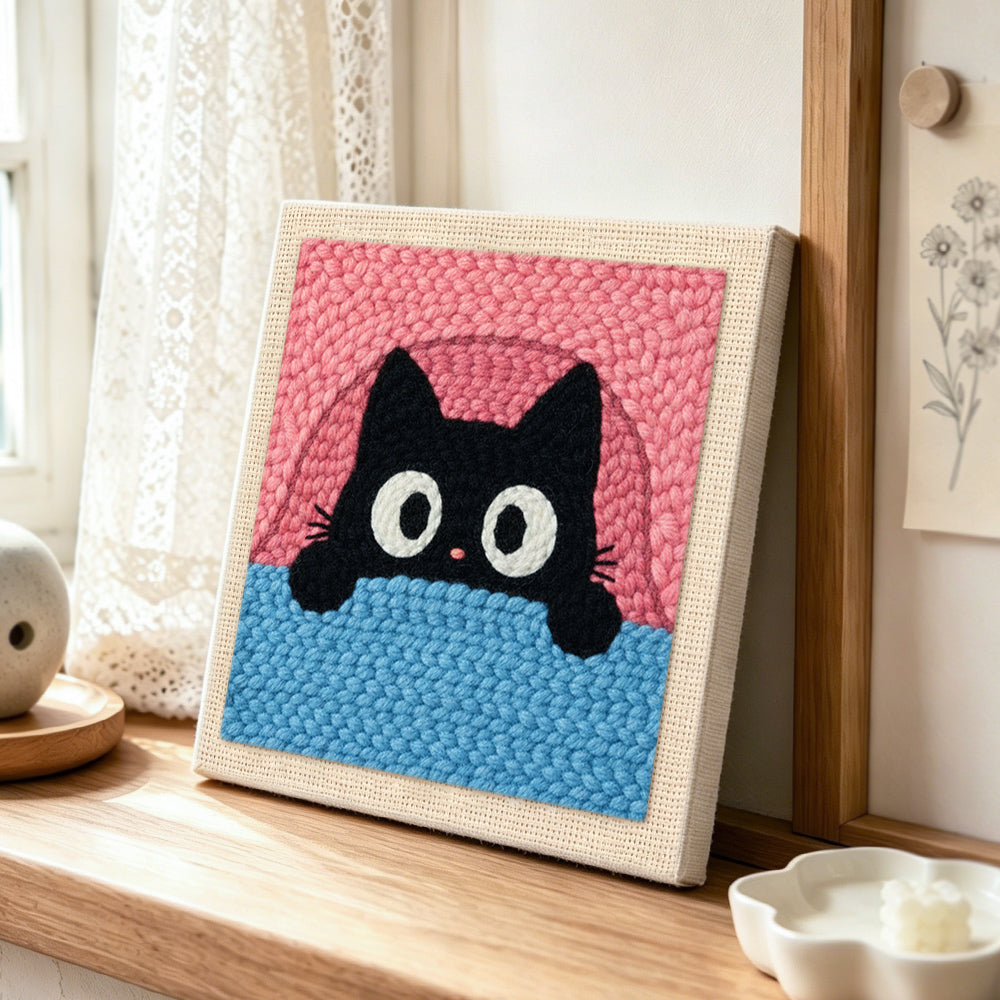 Funny peeking kitten punch needle artwork displayed on a table