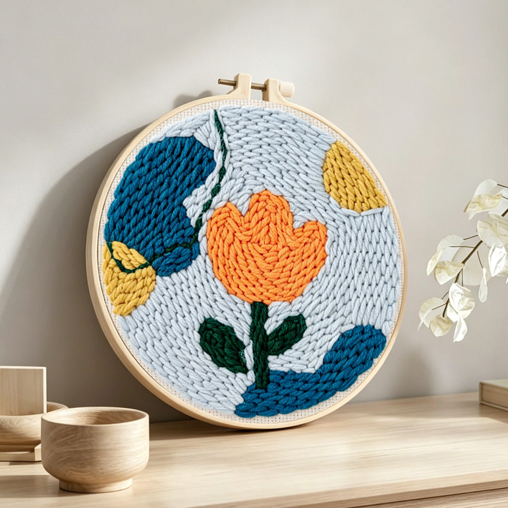 Geometric orange tulip punch needle artwork displayed on a table