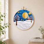 Giant spiral half-moon and snowy tower house needle felt wall art displayed in a bright home interior