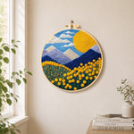 Giant sun, mountains and yellow flowers needle felt wall art displayed in a bright home interior
