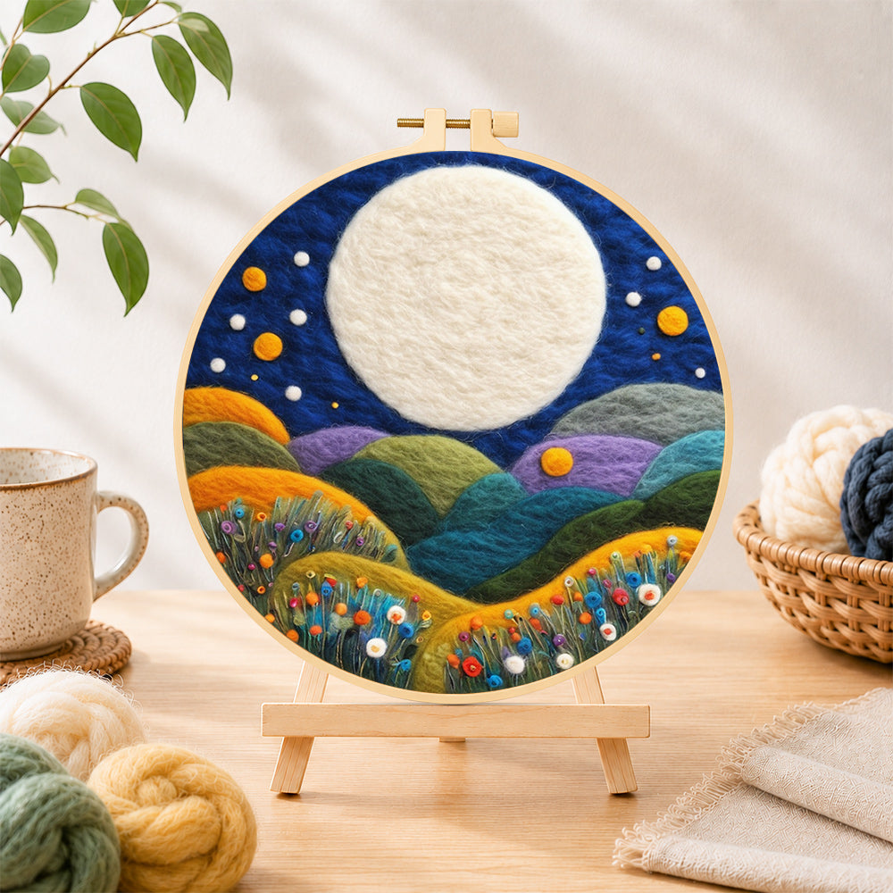 Finished giant white moon over colourful flower hills needle felting displayed on a wooden easel