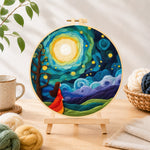 Finished girl in red dress under swirling starry night needle felting displayed on a wooden easel