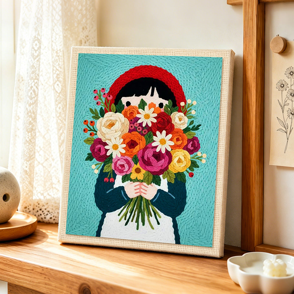Girl in red headscarf holding flowers punch needle artwork displayed on a table