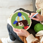 Creating handmade girl with striped beanie and rose punch needle artwork