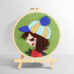 Girl with striped beanie and rose punch needle kit for beginners