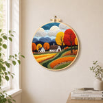 Golden autumn tree and rolling hills needle felt wall art displayed in a bright home interior