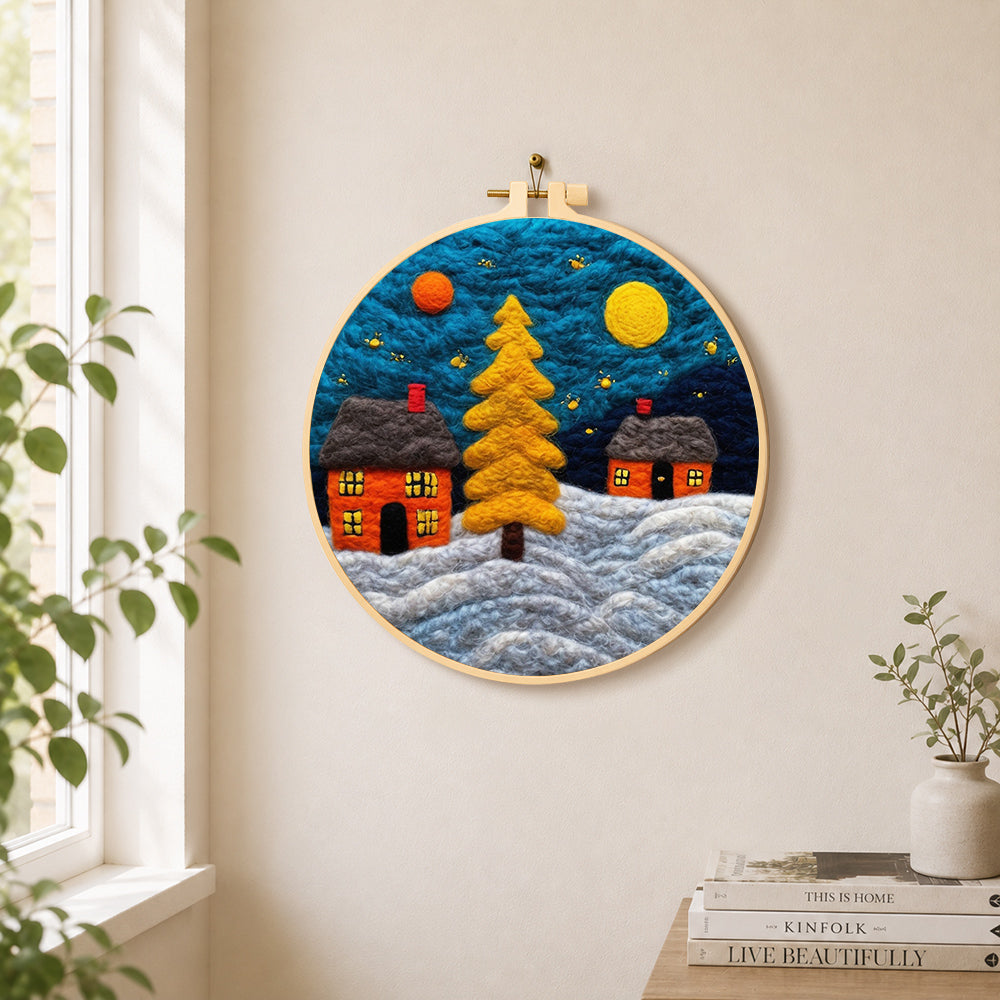Golden christmas tree and snowy cabins needle felt wall art displayed in a bright home interior