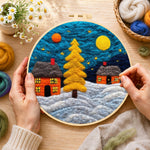 Creating the golden christmas tree and snowy cabins wool painting by hand with a felting needle