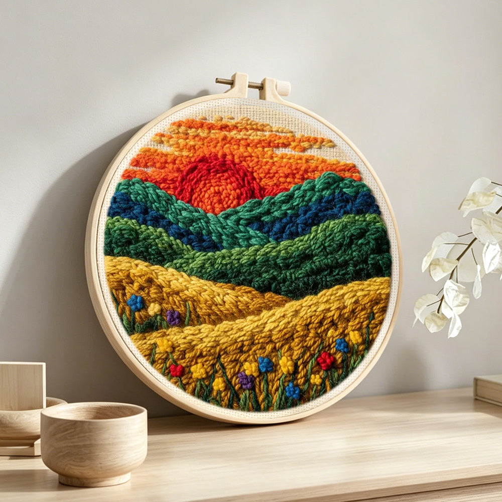 Golden field and green hills at sunset punch needle artwork displayed on a table