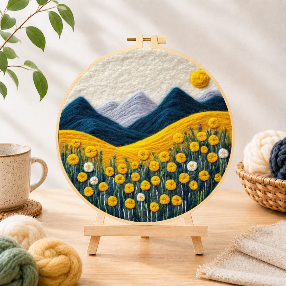 Finished golden flower field and snowy peaks needle felting displayed on a wooden easel