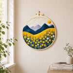 Golden flower field and snowy peaks needle felt wall art displayed in a bright home interior