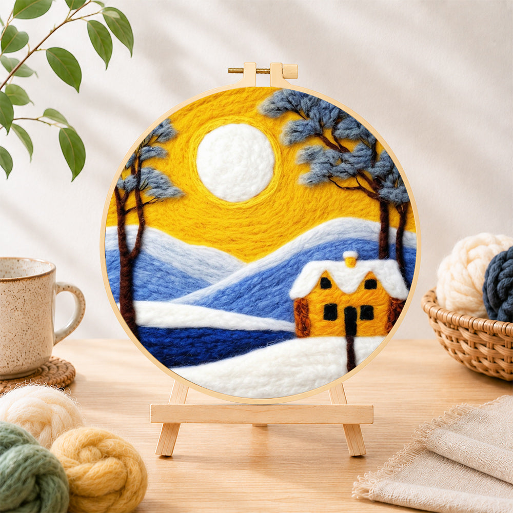 Finished golden sun and blue mountain snowscape needle felting displayed on a wooden easel