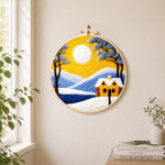 Golden sun and blue mountain snowscape needle felt wall art displayed in a bright home interior