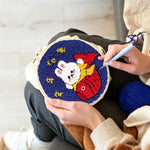 Creating handmade good fortune bunny holding a koi fish punch needle artwork