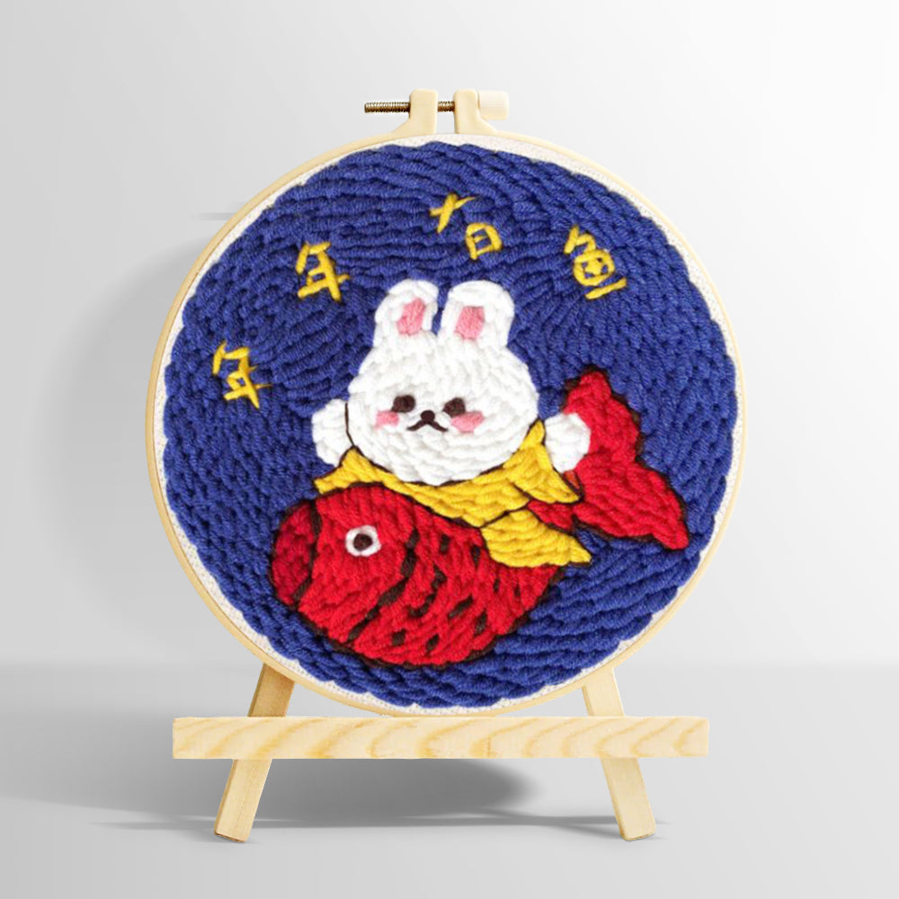 Rood fortune bunny holding a koi fish punch needle kit for beginners