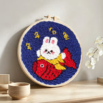 Rood fortune bunny holding a koi fish punch needle artwork displayed on a table