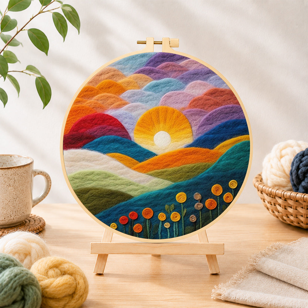 Finished gradient clouds, bright yellow sunset and colourful hills needle felting displayed on a wooden easel