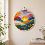 Gradient clouds, bright yellow sunset and colourful hills needle felt wall art displayed in a bright home interior