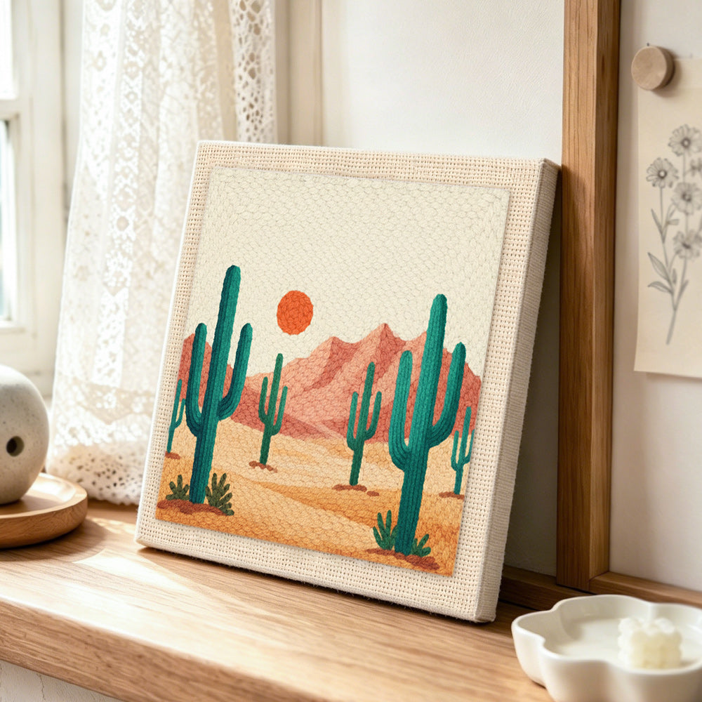 Green cactus and pink mountains punch needle artwork displayed on a table