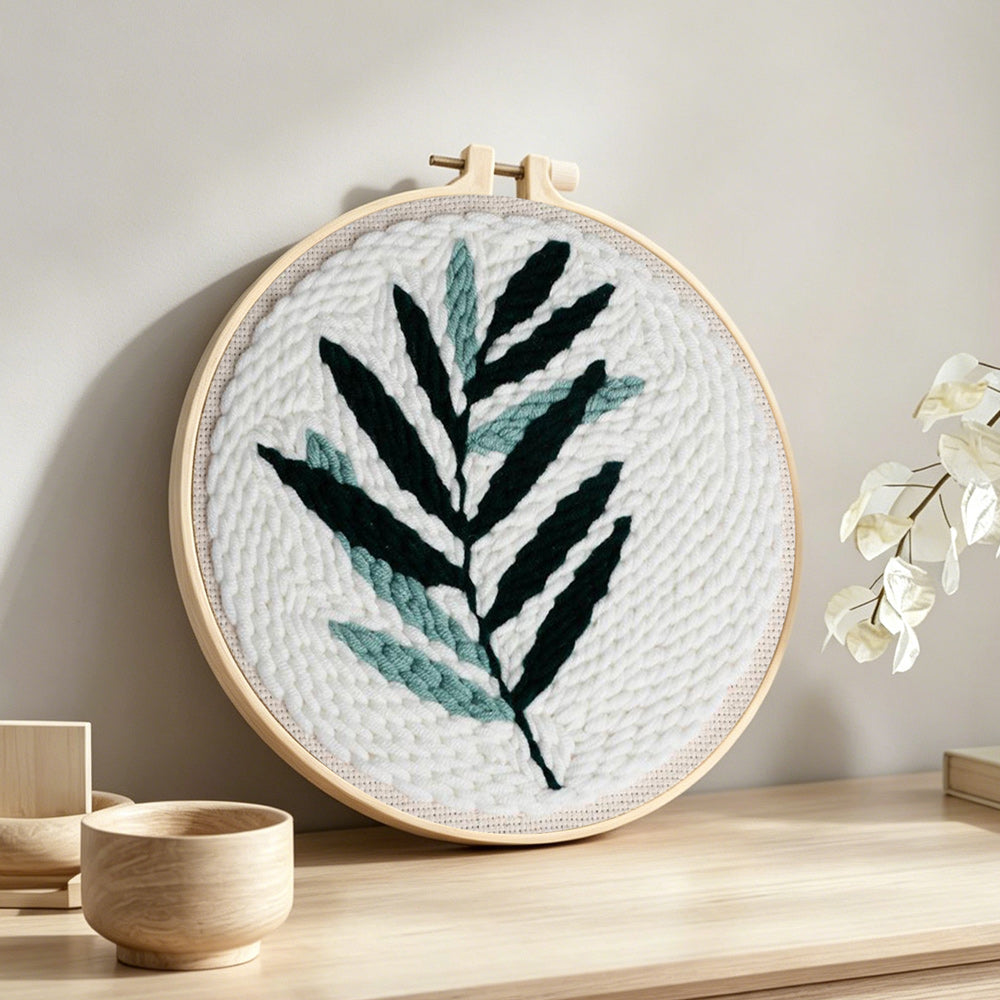 Green fern leaf punch needle artwork displayed on a table