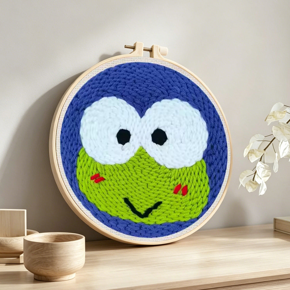 Green frog with big eyes punch needle artwork displayed on a table