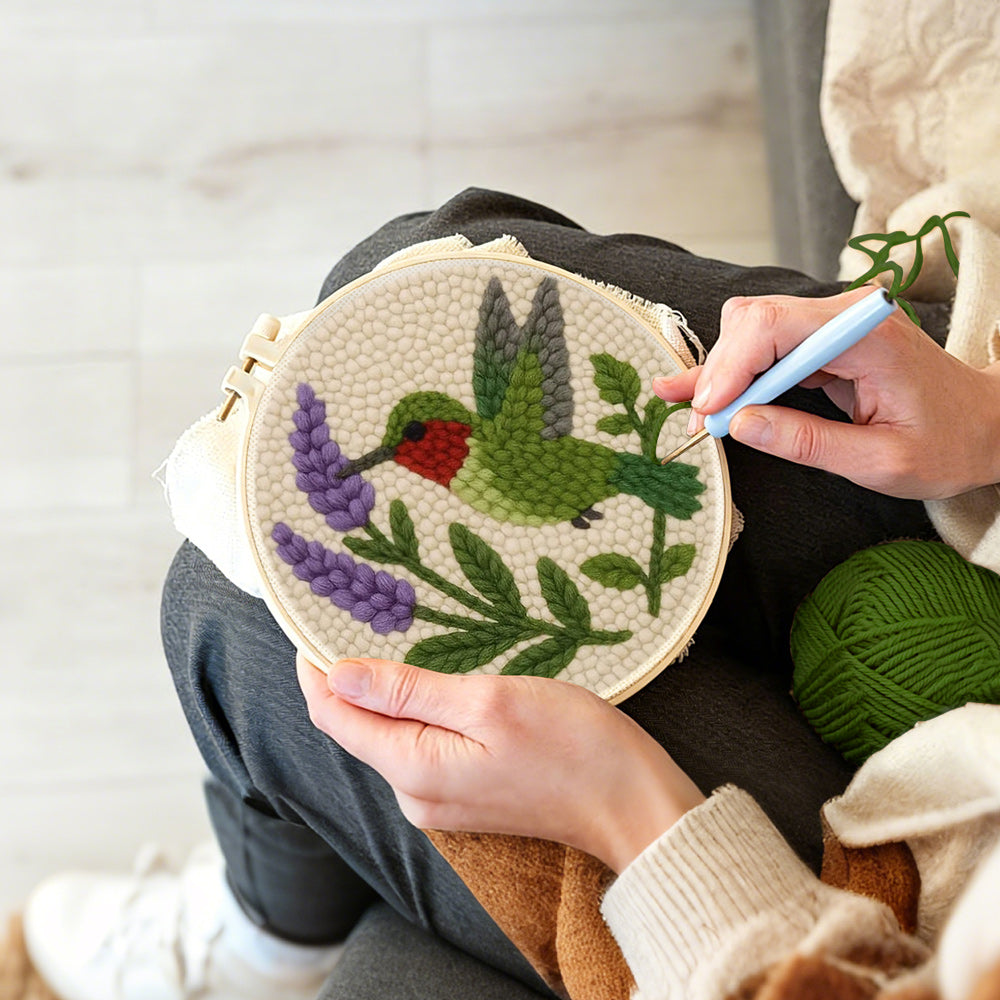 Creating handmade green hummingbird and purple flower punch needle artwork