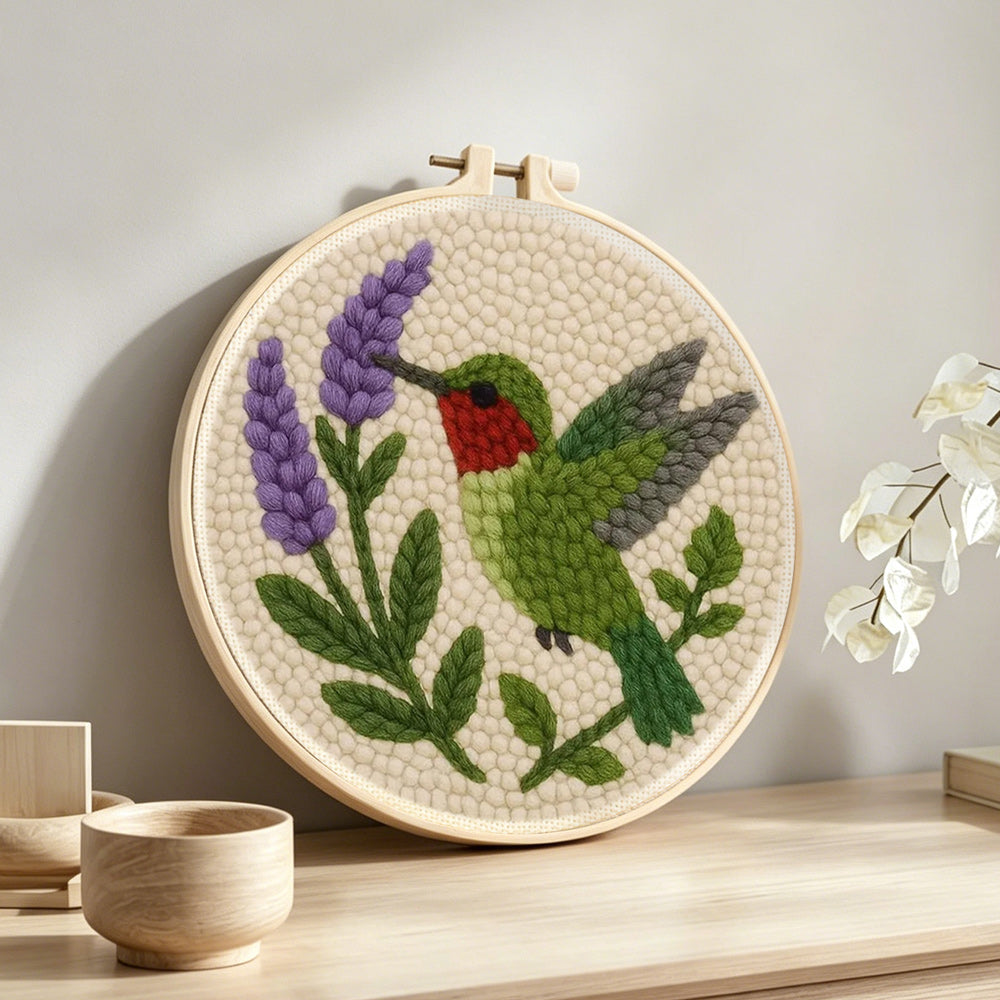 Green hummingbird and purple flower punch needle artwork displayed on a table